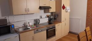 a kitchen with wooden cabinets and a sink and a microwave at Gästezimmer Salzgitter II in Wolfenbüttel in Wolfenbüttel