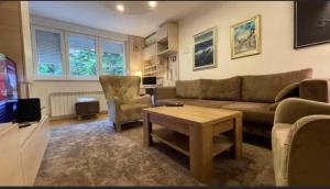 uma sala de estar com um sofá, uma mesa e uma televisão em Apartman Uma em Sarajevo