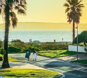 two people walking down a sidewalk near the beach at BEACH HOUSE MOSSELRIVIER in Langebaan