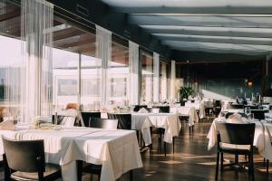una sala da pranzo con tavoli e sedie bianchi e finestre di Schützen Steffisburg a Thun