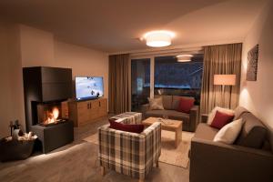 a living room with a couch and a fireplace at ArlbergResort Klösterle in Klösterle am Arlberg