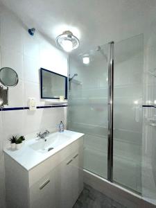 a white bathroom with a sink and a shower at Admirals Suite, Gibraltar in Gibraltar