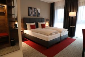 a bedroom with a large bed with red pillows at Hotel INCLUDiO in Regensburg