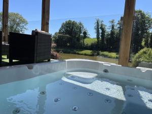 a jacuzzi tub with a view of a yard at Oak Lodge, South View Lodges, Exeter in Exeter