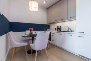 a kitchen with white cabinets and a table and chairs at Apartamenty Polanki Aqua BASENY & SPA Kołobrzeg by Renters Prestige in Kołobrzeg