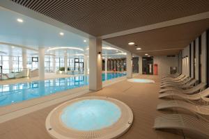 una grande piscina con sedie in un edificio di Apartment Polanki Aqua Kołobrzeg by Renters Prestige a Kołobrzeg