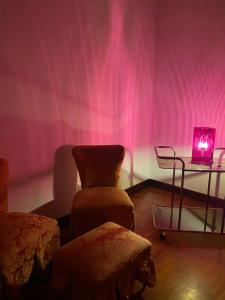 a pink room with a chair and a table with a light at PALAZZO PORCARI in Lecce