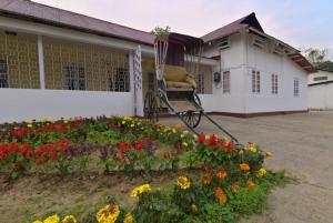 a house with a chair and flowers in front of it at The Sumola House in Jorhāt