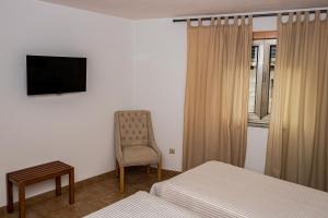 a bedroom with two beds and a chair and a television at Casas Campo Cimo da Quinta in Miranda do Douro