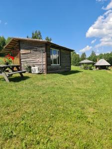 a log cabin with a picnic table in the grass at Rezidence Kurzeme in Kāķīši