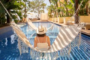 a woman sitting in a hammock by a pool at Iberostar Selection Jardín del Sol Suites - Adults Only in Santa Ponsa