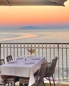 a table on a balcony with a view of the ocean at Hôtel Des Gouverneurs in Bastia