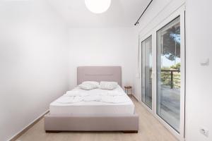 a white bedroom with a bed and a large window at Brand new maisonette in Chanioti, Chalkidiki in Hanioti