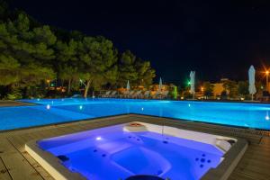 una vasca da bagno accanto alla piscina di notte di VILLA ROSA MEDITERRANEA a Marina di Pescoluse