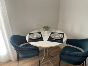 a table with two blue chairs and a white table with plates at Studio pour 2 avec terrasse au pied de la Cité : ma pierre à l’édifice in Carcassonne
