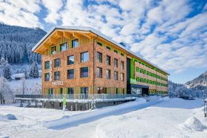 a hotel in the snow in front of a mountain at Explorer Hotel Garmisch in Farchant