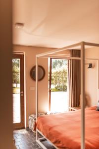 Schlafzimmer mit Himmelbett und Glastür in der Unterkunft B&B Maison Lize in Lievegem