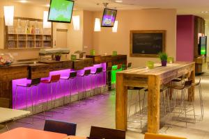 um restaurante com bancos de bar roxos e verdes em Explorer Hotel Garmisch em Farchant