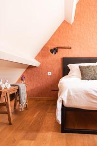 a bedroom with orange walls and a bed and a table at B&B Maison Lize in Lievegem