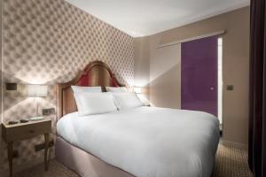a bedroom with a large white bed and a window at Hôtel La Parizienne - Proche Montparnasse in Paris