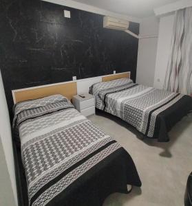 2 Betten in einem Zimmer mit schwarzer Wand in der Unterkunft Hostal la Campana in La Línea de la Concepción