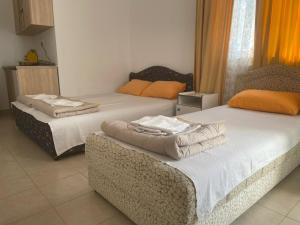 two beds in a room with orange curtains at Apartmani Jacimovic in Čanj