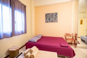 una camera da letto con un letto con lenzuola viola e una finestra di Independent Apartment at Lykavitos 1 bed 2 pers ad Atene