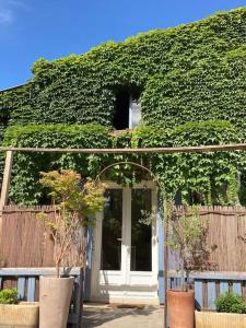 a building covered in green ivy with a white door at Cabanon Ecurie Maestoso in Lançon-Provence