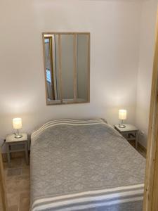 ein Schlafzimmer mit einem Bett mit zwei Lampen und einem Spiegel in der Unterkunft Cabanon Ecurie Maestoso in Lançon-Provence