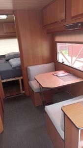 a small room with a desk and a bed and a table at Karavan 1 v areálu Koupaliště Bystré v Orlických horách in Bystré