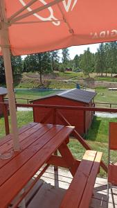 a picnic table with an orange umbrella and a picnic bench at Karavan 1 v areálu Koupaliště Bystré v Orlických horách in Bystré