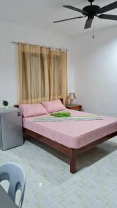 een groot bed in een kamer met een plafondventilator bij Babas Guesthouse in Moalboal