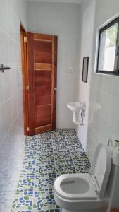 a bathroom with a toilet and a sink and a door at Babas Guesthouse in Moalboal