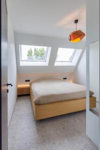 a bedroom with a bed and two windows at Apartment L'O Reine in Sint-Pieters-Leeuw