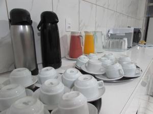 un mostrador con tazas y platillos en una mesa en Teodoro Palace Hotel a 5 minutos do Brás e Bom Retiro, en São Paulo