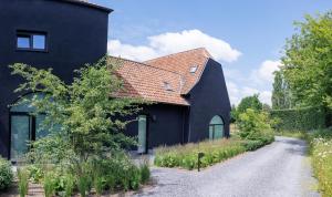 ein schwarzes Haus mit rotem Dach und Schotterstraße in der Unterkunft Apartment L'O Reine in Sint-Pieters-Leeuw
