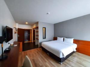 a hotel room with a bed and a television at Comet Hotel Surat Thani in Surat Thani