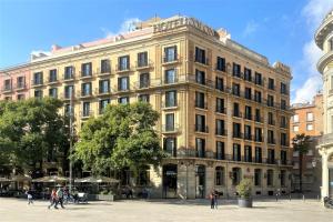 un grand bâtiment avec des personnes qui marchent devant lui dans l'établissement Colón Hotel Barcelona, à Barcelone