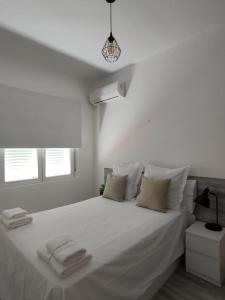a white bedroom with a large white bed with towels on it at La Mansión del Toledano in Granada