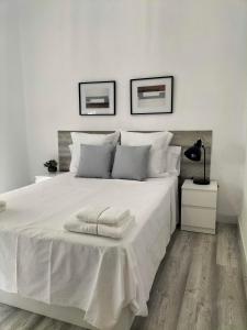 a white bedroom with a large bed with white sheets at La Mansión del Toledano in Granada