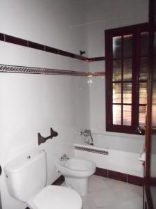a white bathroom with a toilet and a window at Casa rural Villa Manuela in Cazalla de la Sierra