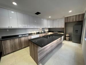 uma grande cozinha com armários brancos e um balcão preto em Durban Italian villa 1&2 em Durban