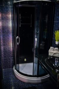 a glass shower in a bathroom with a sink at Medius Park Apartment in Sandanski