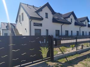 une maison avec une clôture devant elle dans l'établissement Apartamenty Bursztynowa Zatoka - Łeba - Nowęcin, à Nowecin