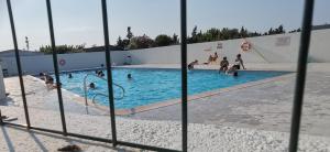 a view of a swimming pool through a fence at Chalet en bois "Le Libellule" in Sigean