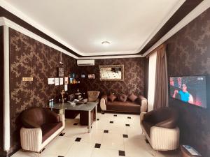 sala de estar con 2 sillas, mesa y TV en Hotel Rich en Tiflis