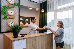 un homme et une femme debout devant une caisse enregistreuse dans l'établissement DOMA HOSTEL, à Almaty