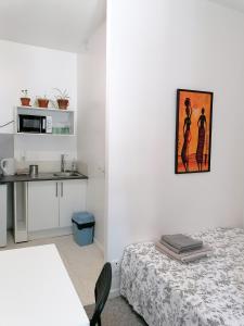 um pequeno quarto branco com uma cama e uma cozinha em Cool Places em Limoges