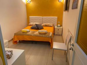 マルサラにあるDiVino Marsala centroの小さなベッドルーム(オレンジのシーツと枕が備わるベッド付)