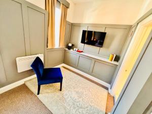 a room with a blue chair and a television at George & Dragon Hotel in Buckinghamshire